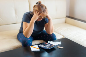 worried business owner stresses over numbers and a calculator concerned about replacing the hail damaged roof on her austin business, roofing companies in austin, austin tx, roofing inspection in austin