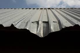 hail damage on edge of commercial standing seam metal roof on a business building, austin roofing company, roofing company dripping springs, roof repair austin, roof replacement austin